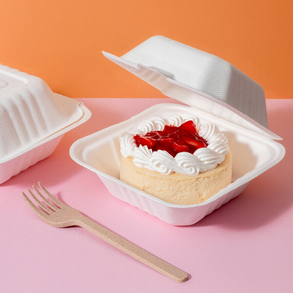 A white compostable sugarcane fiber clamshell take-out container holding a small dessert, shown with a wooden fork.