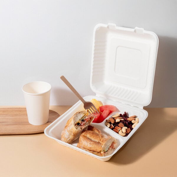 A white, three-compartment compostable clamshell take-out container made from sugarcane fiber, shown with food inside.