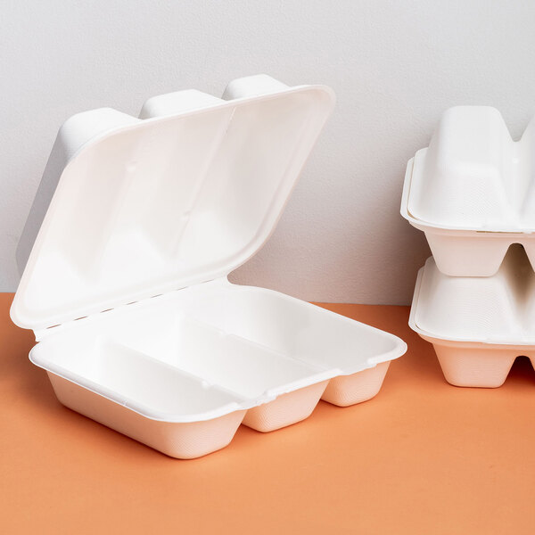 A white, three-compartment compostable clamshell take-out container made from sugarcane fiber.