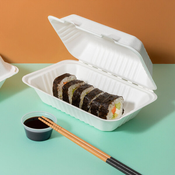 A white compostable sugarcane fiber clamshell take-out container holding sushi rolls, accompanied by a small cup of soy sauce and a pair of chopsticks.