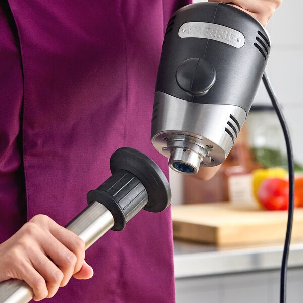 A Waring WSB265 Big Stik 18-inch heavy-duty 2-speed immersion blender being assembled in a kitchen setting.