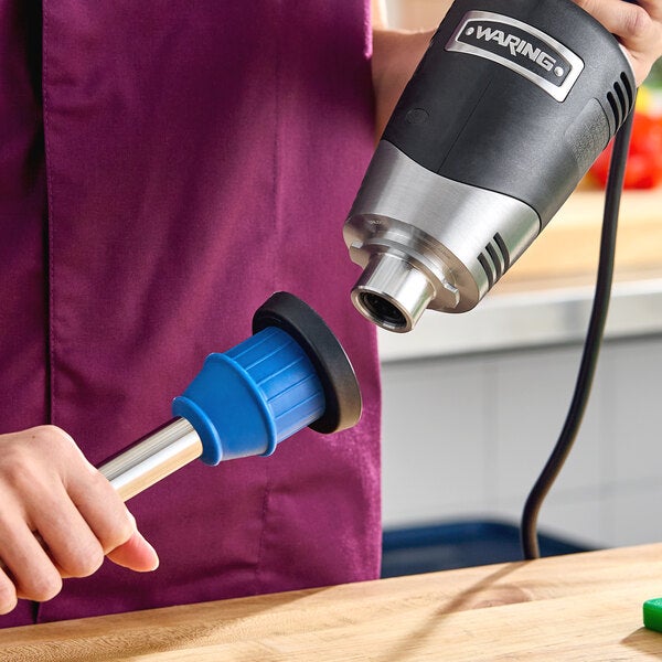 A Waring Quik Stik Plus 10-inch medium-duty variable-speed immersion blender being assembled or cleaned.