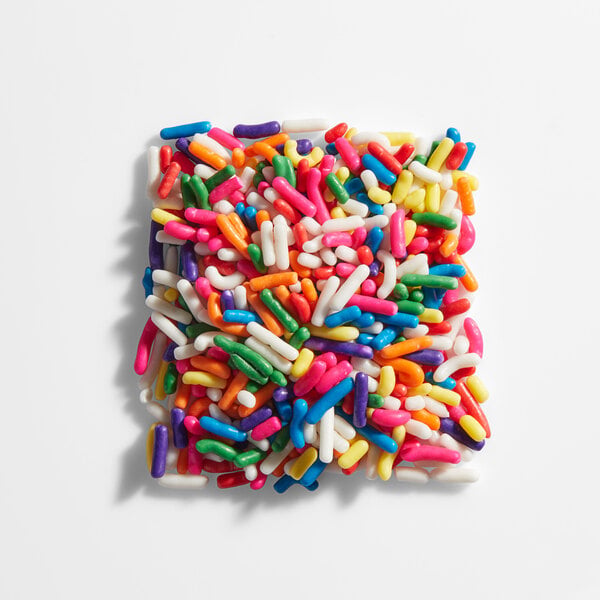 A square-shaped pile of colorful rainbow sprinkles arranged on a white surface.