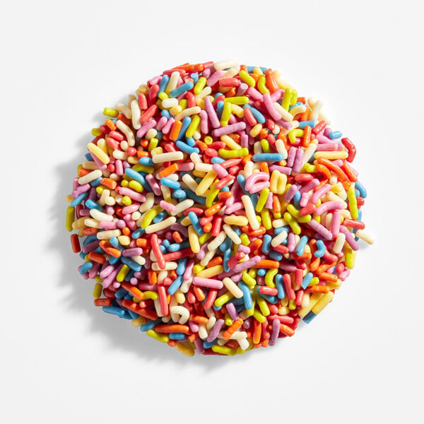 A round cookie or confection covered in colorful rainbow sprinkles, viewed from above on a white background.