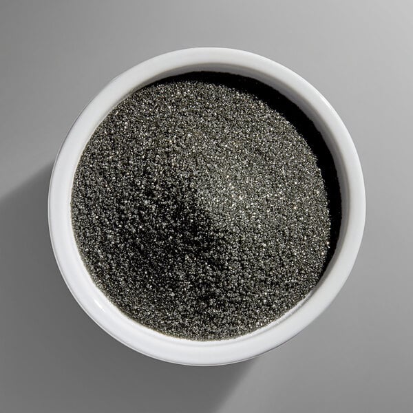 A white bowl filled with fine, black, glittery granules resembling sanding sugar.