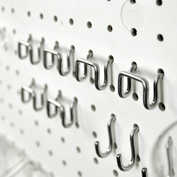 A set of metal hooks attached to a white pegboard, part of a pegboard accessory kit.