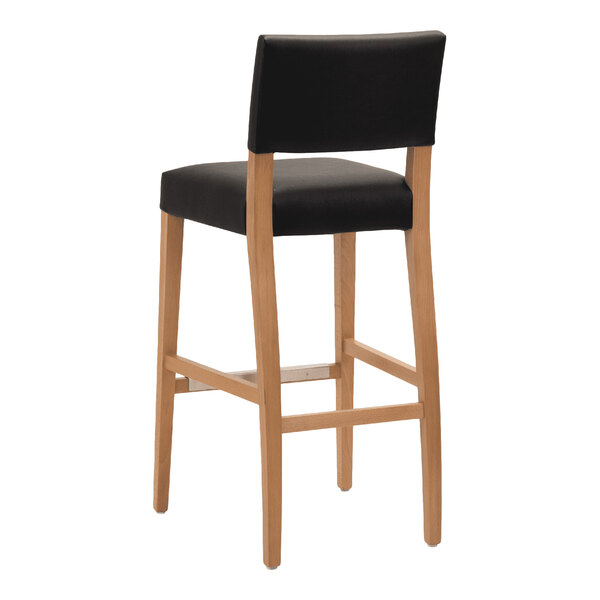 A bar stool with a natural beech wood frame and a black faux leather seat and backrest.