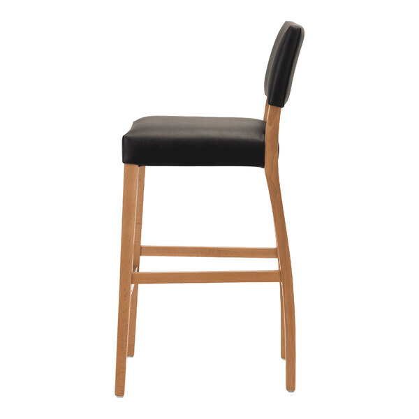 A bar stool with a natural beech wood frame and a black faux leather seat and backrest.