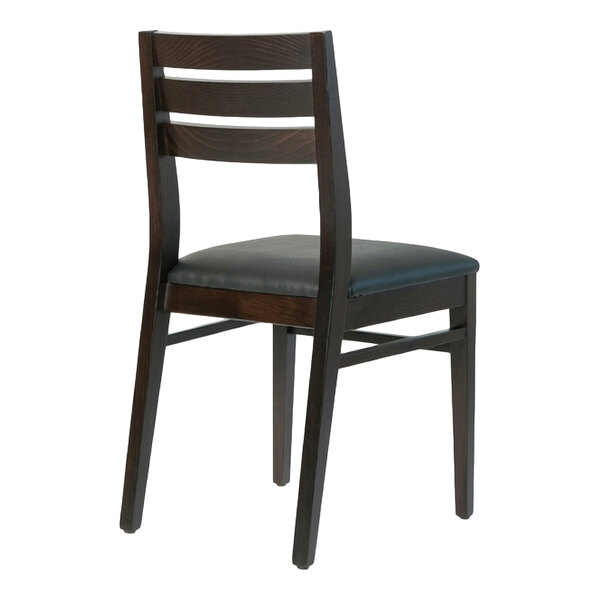 A dark brown beech wood dining chair with a ladder back design and a black faux leather seat.