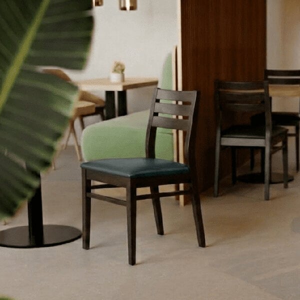 A dark brown beech wood dining chair with a ladder back design and a black faux leather seat.