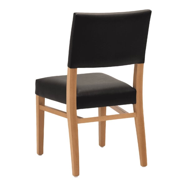 A stackable chair with a natural beech wood frame and black faux leather seat and back.