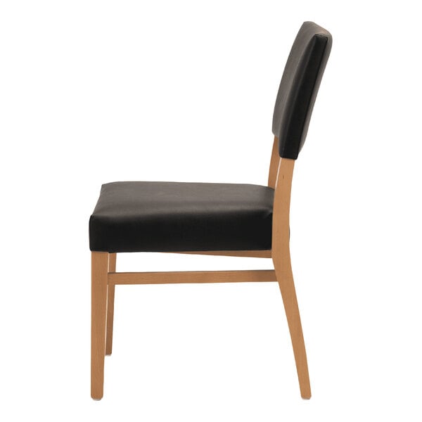 A stackable chair with a natural beech wood frame and black faux leather seat and back.