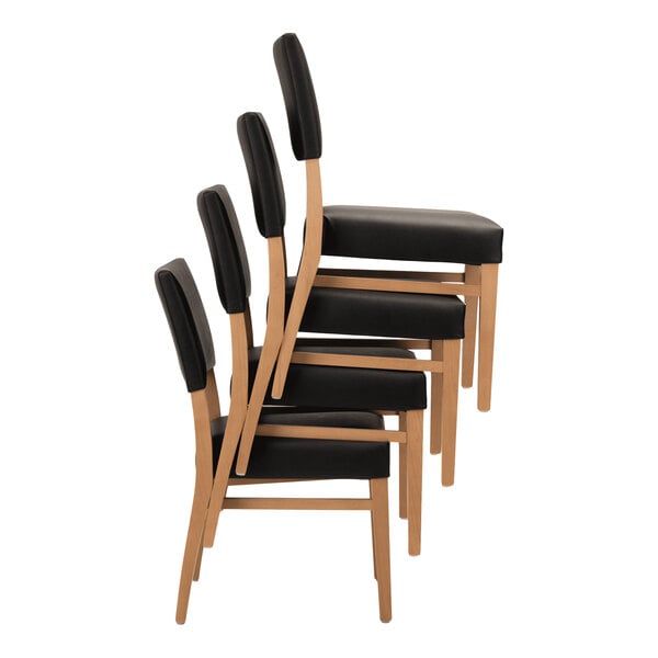 A set of stackable chairs with natural beech wood frames and black faux leather seats and backs.