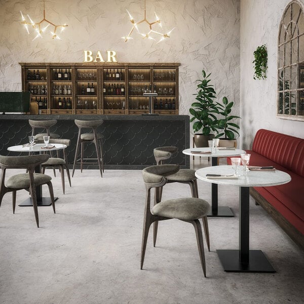 A green faux leather stackable dining chair with a brown wooden frame, placed in a modern bar setting.