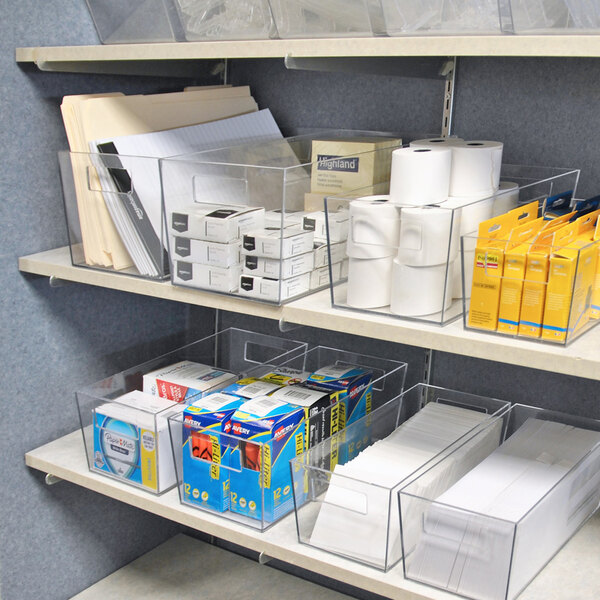 A set of clear plastic tote bins used for organizing office supplies on shelves.