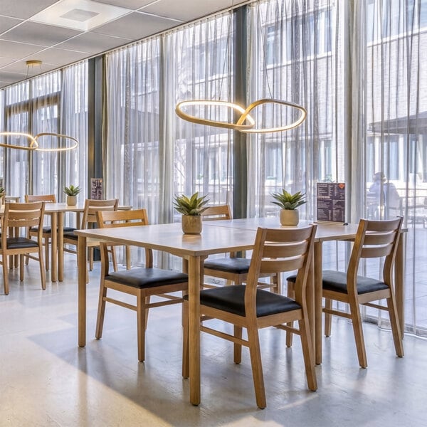 A natural beech wood ladder back dining chair with a black faux leather seat.