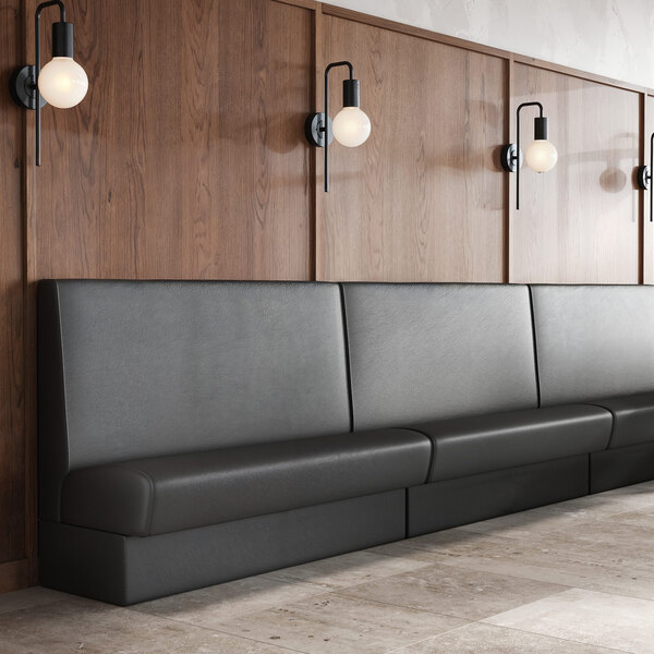 A long, black upholstered wall booth banquette with a high backrest, positioned against a wood-paneled wall.
