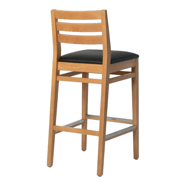 A natural beech wood ladder back bar stool with a black faux leather seat.