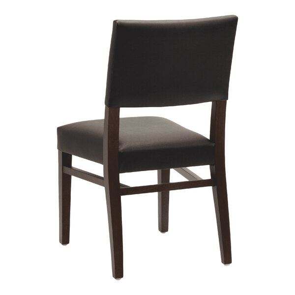 A dark brown beech wood stackable chair with a black faux leather seat and back.