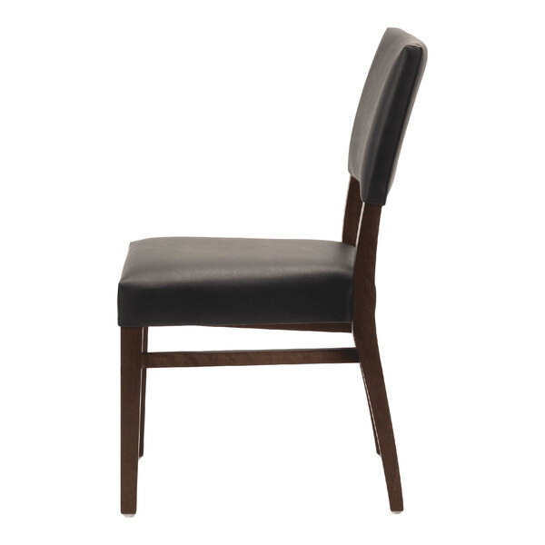 A dark brown beech wood stackable chair with a black faux leather seat and back.