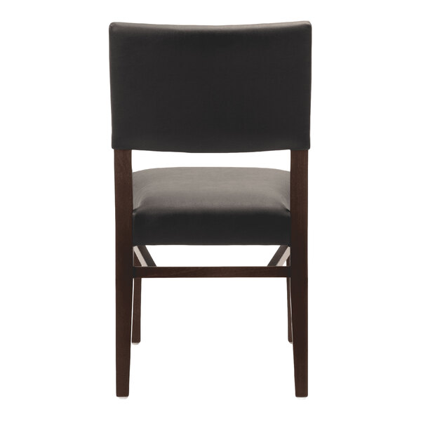 A dark brown beech wood stackable chair with a black faux leather seat and back.