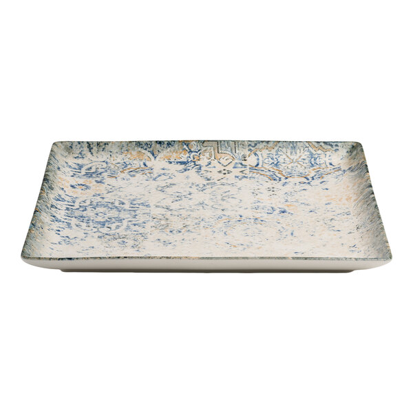 A square blue and white porcelain plate with tan accents and an organic foliate design.