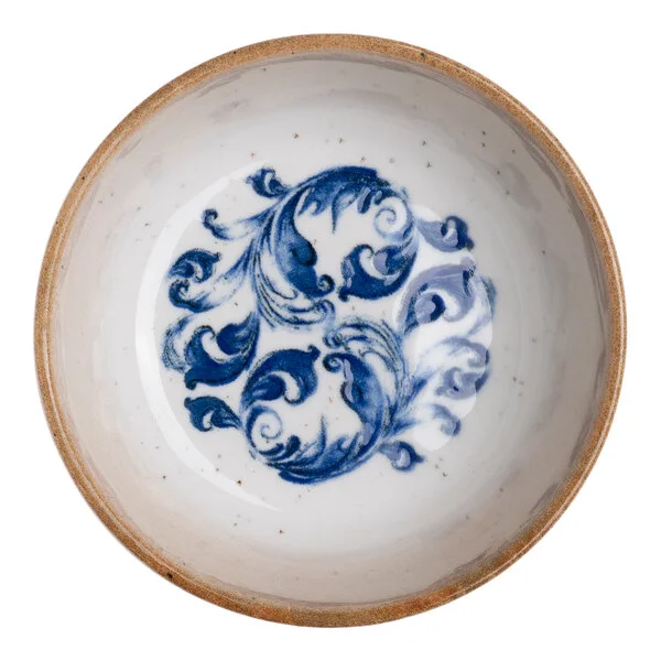 A round white porcelain bowl with a blue floral design in the center and a tan rim.