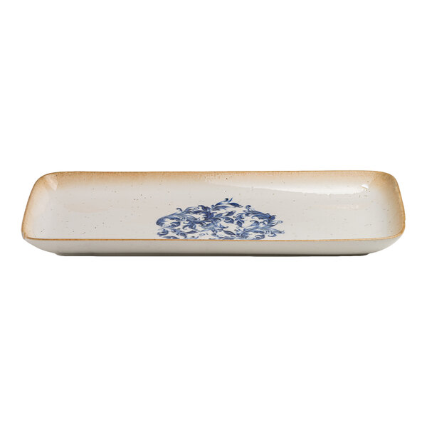 A rectangular white porcelain platter with a blue floral design in the center and a tan rim.