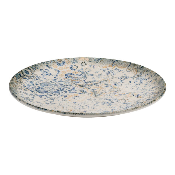 A round blue and white porcelain rimless coupe plate with tan accents and an organic foliate design.