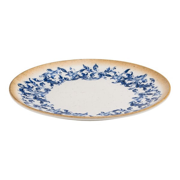A round white porcelain coupe plate with a blue floral edge and tan rim.
