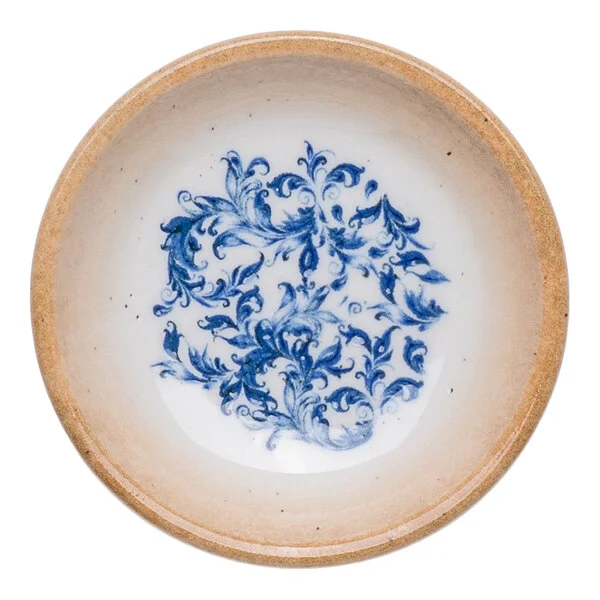 A round white porcelain ramekin with a blue floral design in the center and a tan rim.