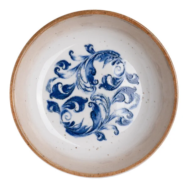 A round white porcelain bowl with a tan rim and a blue floral design in the center.