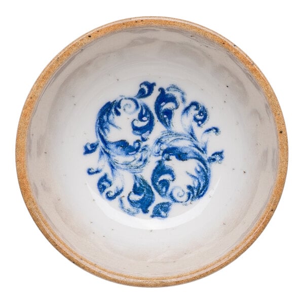 A round white porcelain ramekin with a blue floral design in the center and a tan rim.