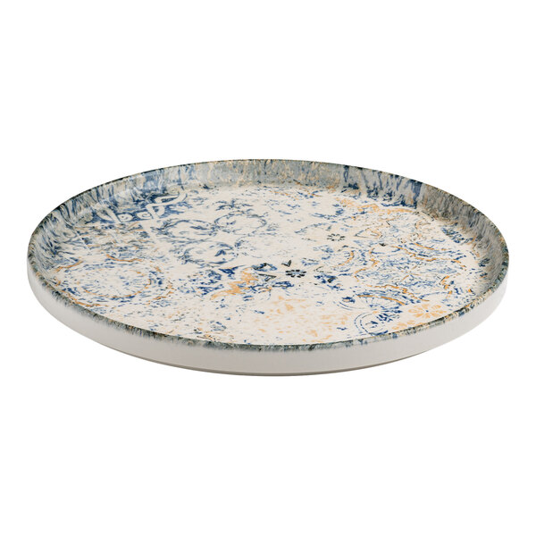 A round blue and white porcelain plate with tan accents, a raised rim, and an organic foliate design.