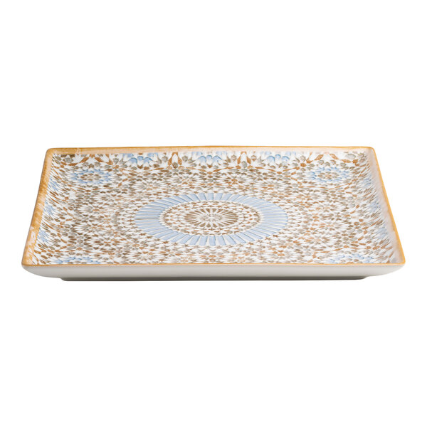 A square porcelain plate with a blue and orange intricate pattern.