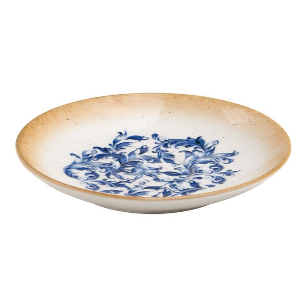 A round white porcelain saucer with a blue floral center design and a tan rim.