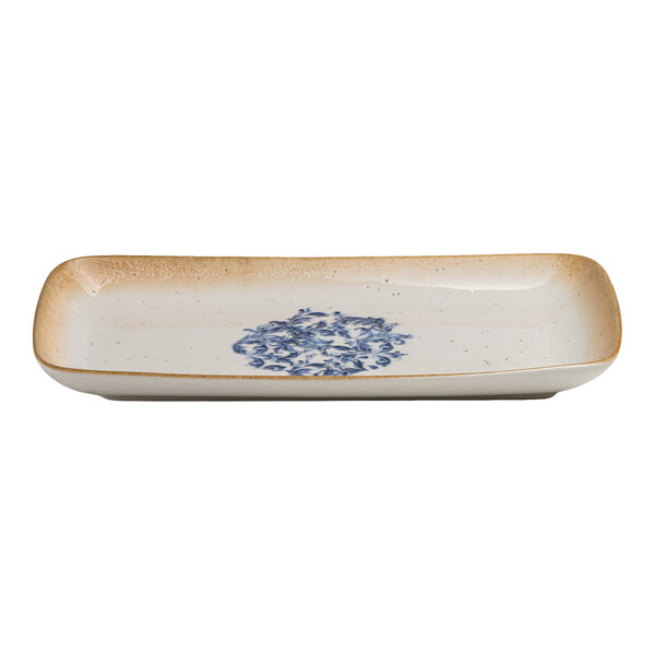 A rectangular white porcelain platter with a blue floral center and a tan rim.