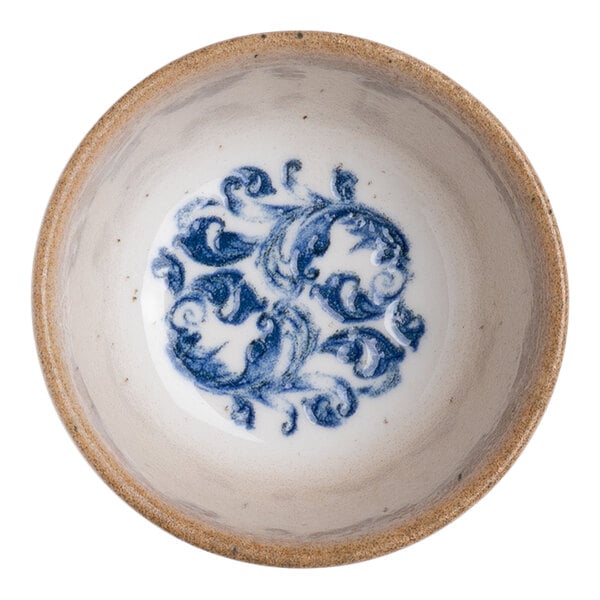 A round white porcelain bowl with a blue floral design in the center and a tan rim.