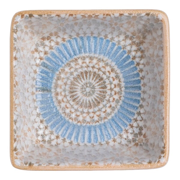 A square blue and orange porcelain ramekin with a radial geometric design.