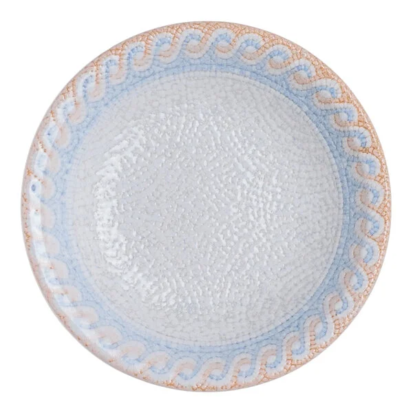 A round blue porcelain ramekin with a blue and tan wave design on the rim and a white textured interior.