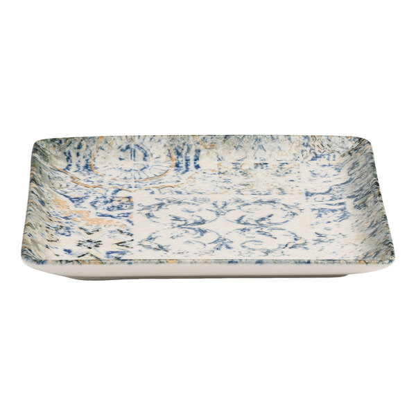A square blue and white porcelain plate with tan accents and an organic foliate design.