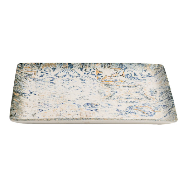 A square blue and white porcelain plate with tan accents and an organic foliate design.