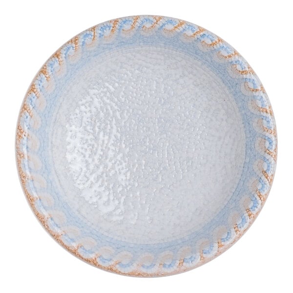 A round blue porcelain ramekin with a blue and tan wave design on the rim and a white interior.