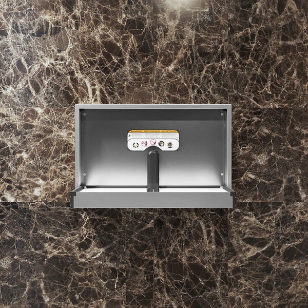A recessed horizontal stainless steel baby changing station mounted on a marble-patterned wall.
