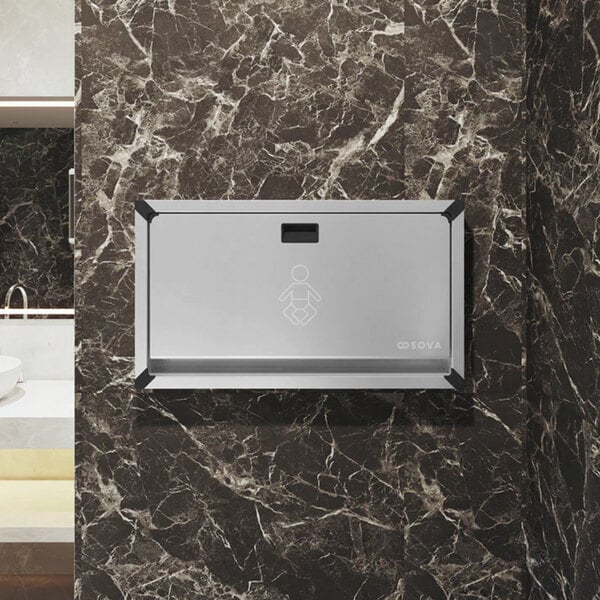A stainless steel surface-mount horizontal baby changing station attached to a marble-patterned wall.