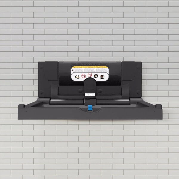 A black stainless steel surface-mount horizontal baby changing station attached to a tiled wall.