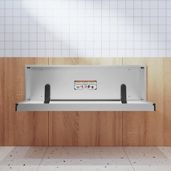 A recessed extended-length stainless steel changing station or table designed for adults, children, or special needs use.