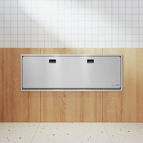 A recessed, extended-length stainless steel adult and child special needs changing station mounted on a wall.