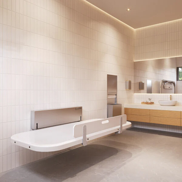 A wall-mounted adult changing station with safety rails in a modern restroom.