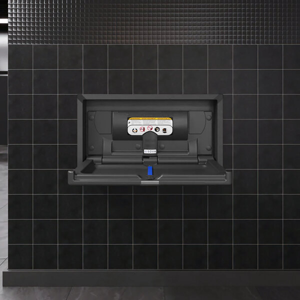 A black recessed horizontal baby changing station with a black stainless steel frame mounted on a tiled wall.